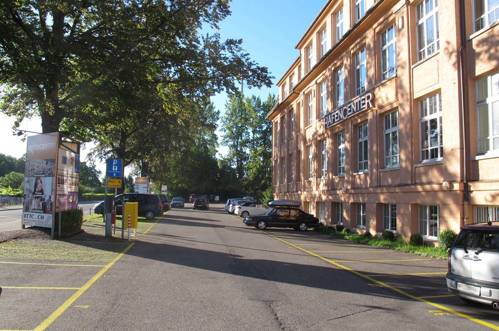 Parkplatzbereich vor dem Bodensee Technologie & Trade Center mit mehreren geparkten Fahrzeugen und Bäumen.